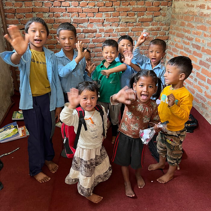 Nepalesische Kinder unterschidelichen Alters winken freudig und aufgeregt in die Kamera