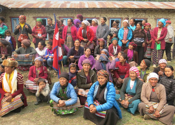 Die Dorfbewohner von Nalidanda haben sich draußen zu einem Gruppenfoto versammelt. Sie stehen und sitzen vor einem gemauerten Gebäude.