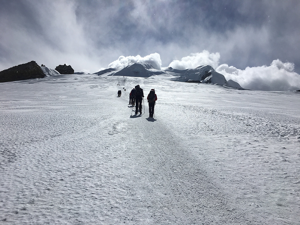 Eine Gruppe Bergsteiger läuft über ein Schneefeld beim Aufstieg zum Mera Peak