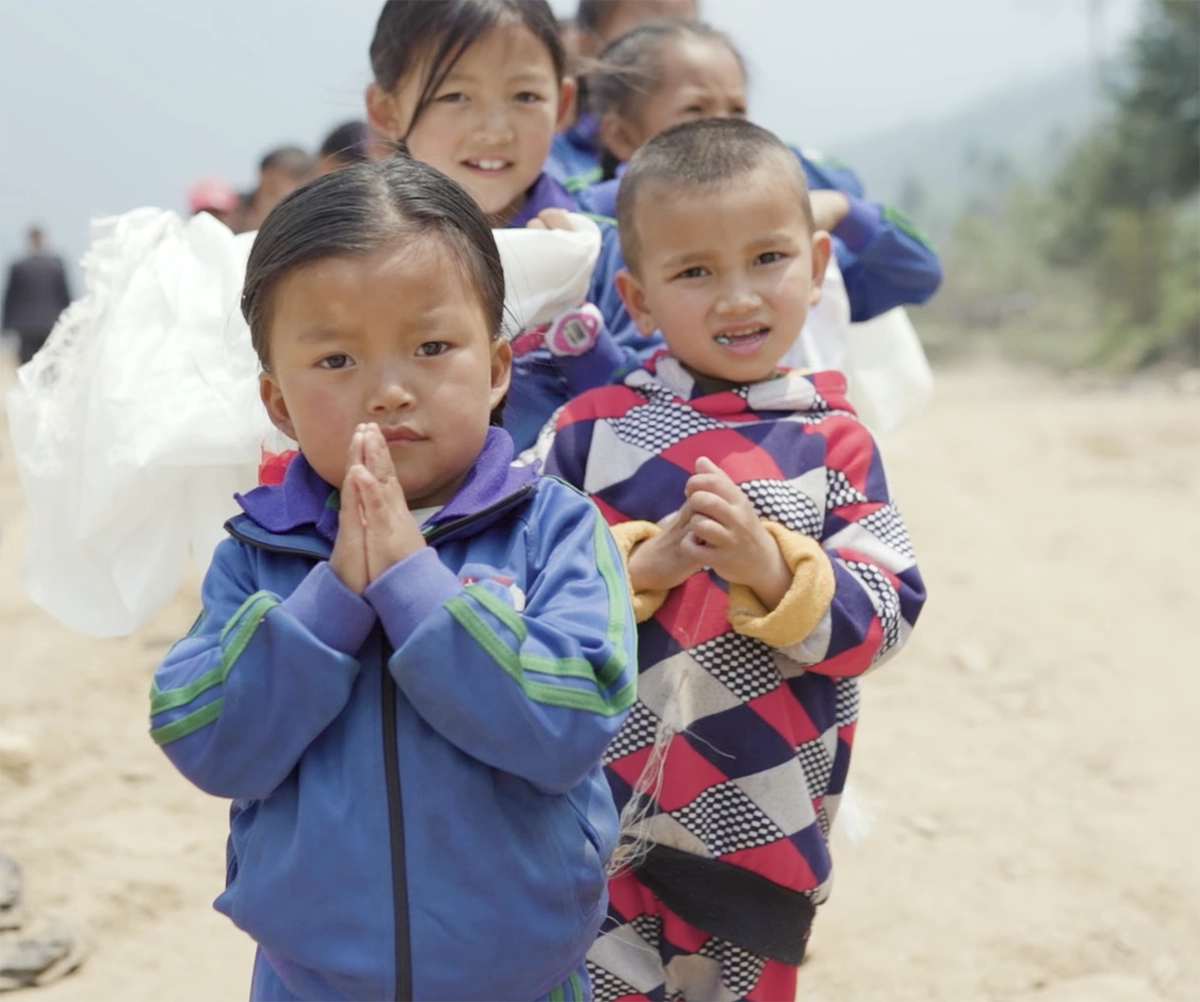 Mehrere nepalesiche Kinder stehen hintereinander im Freien und blicken in die Kamera.